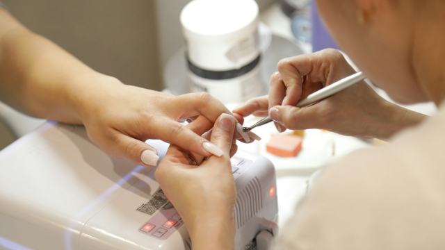 Manicure cuidando das unhas de uma cliente sobre a mesa de atendimento