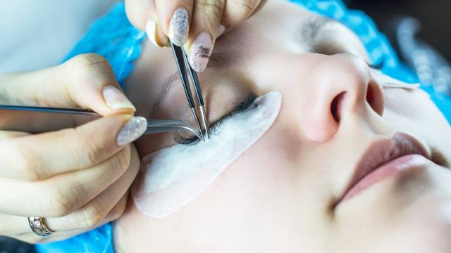 Profissional fazendo procedimento estético na região dos olhos de uma cliente deitada